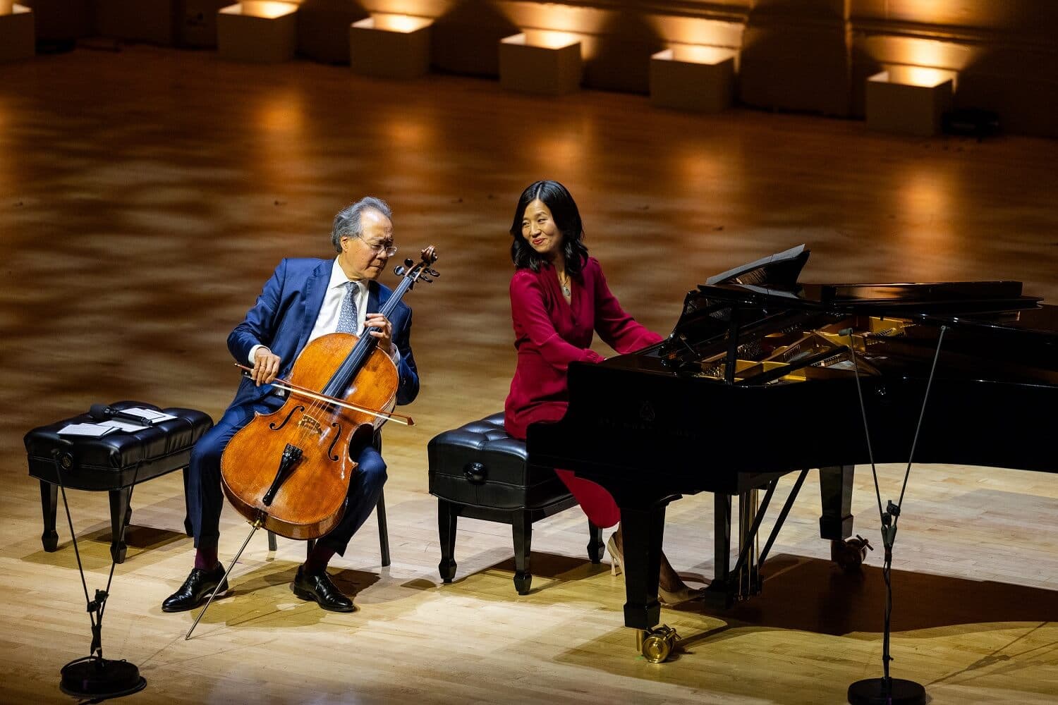 A man playing a cello and a woman playing a piano perform on a stage.